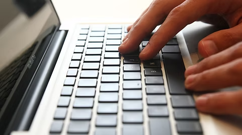 Hands working at a laptop keyboard